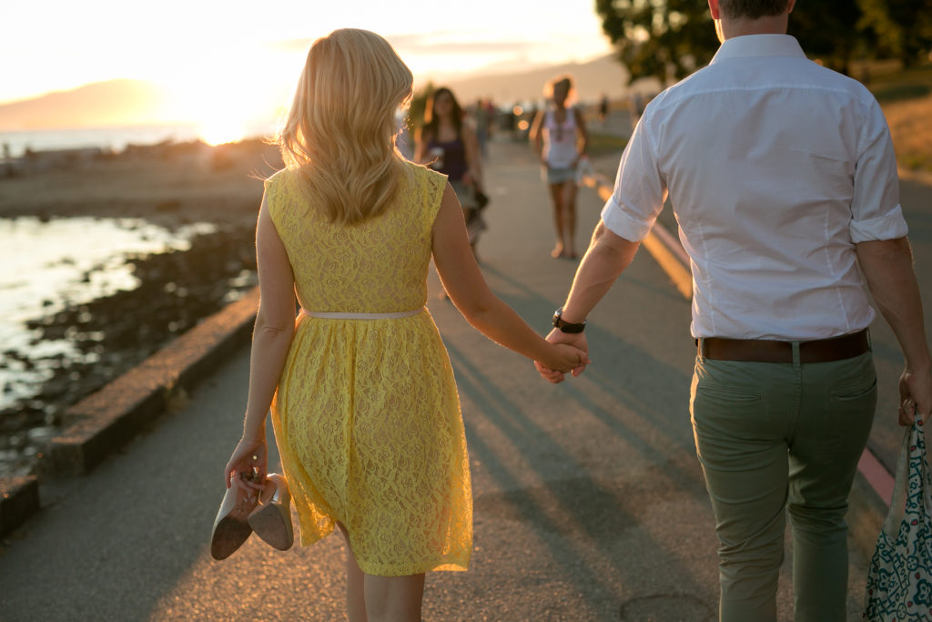 couple walking on seawall at sunset engagement photos