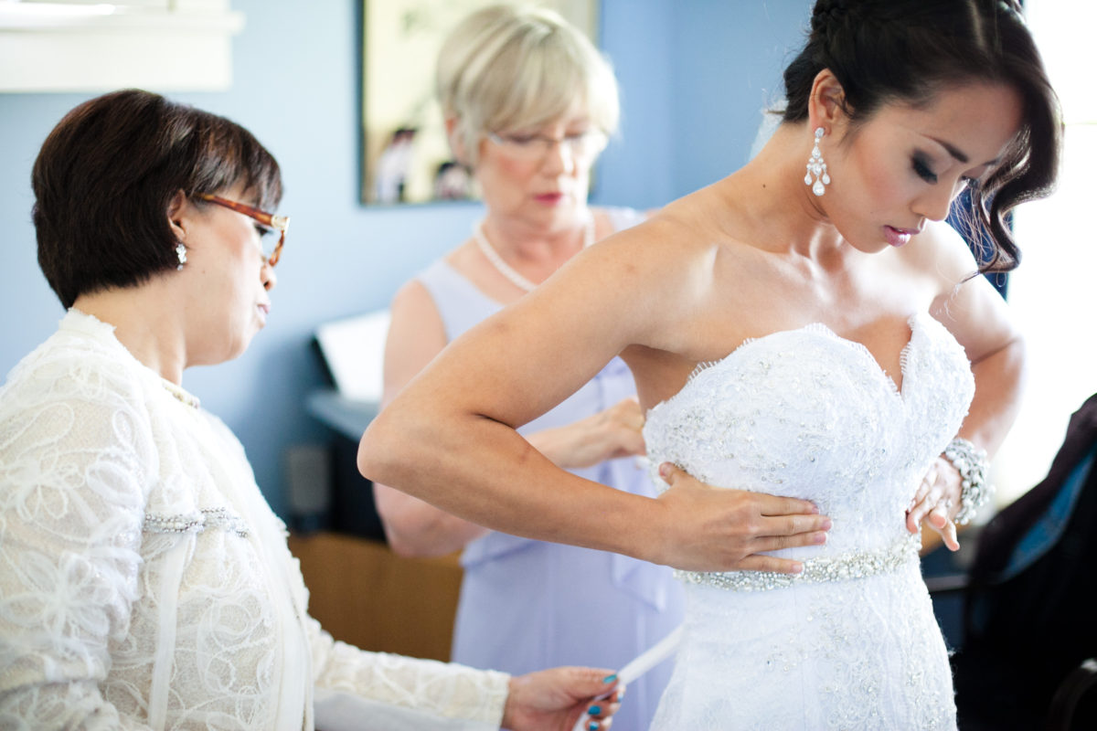 mothers helping bride into wedding dress