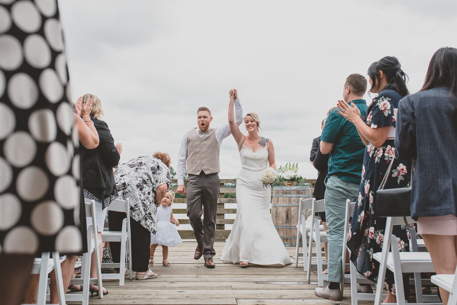 couple coming down the aisle after wedding ceremony on dock at south bonson community centre
