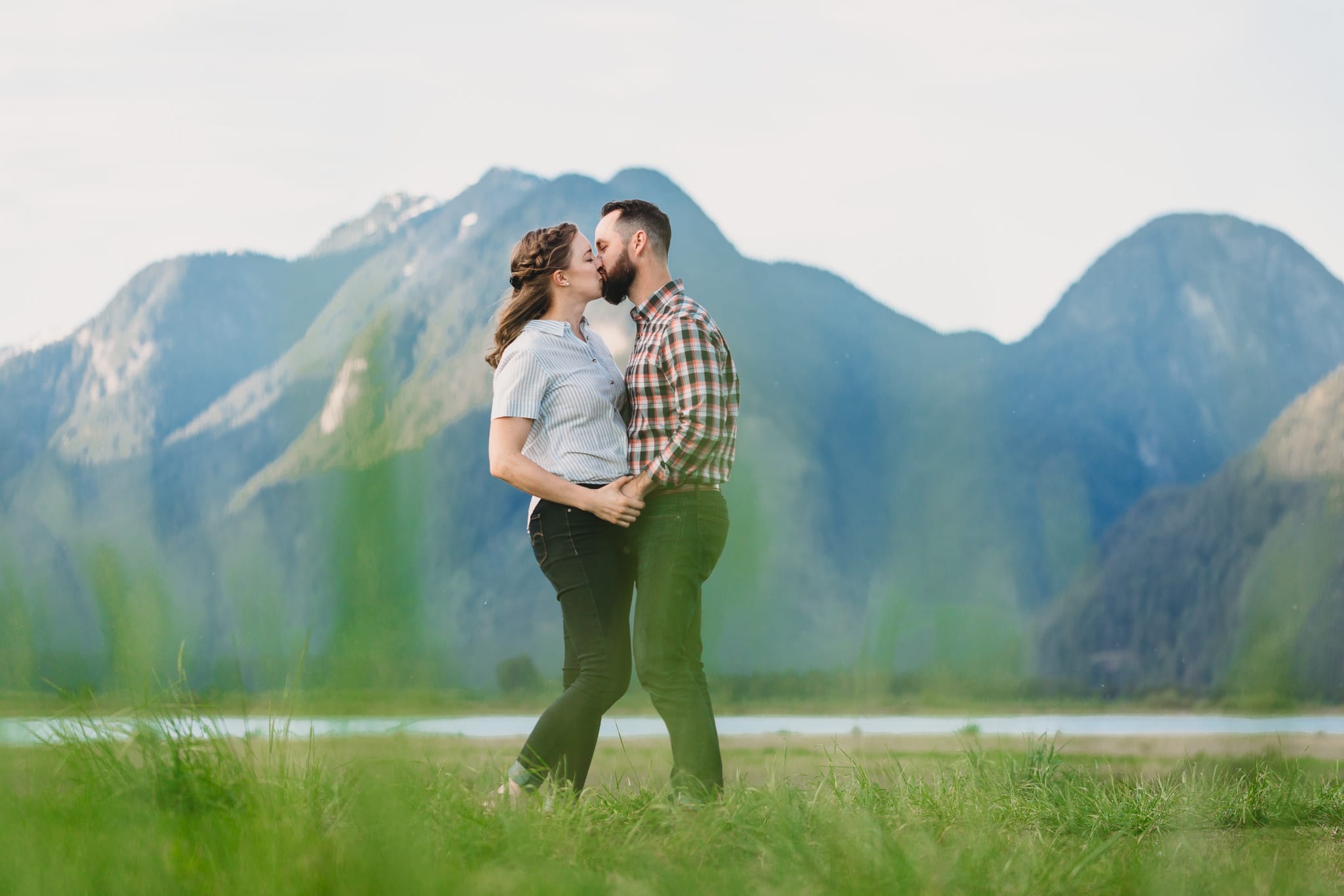 couple kissing at pitt lake engagement session with mountains in background