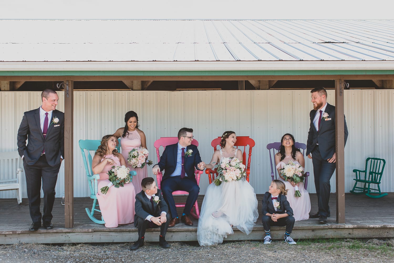 fun and informal wedding party portrait in colourful rocking chairs at hopcott farms barn wedding