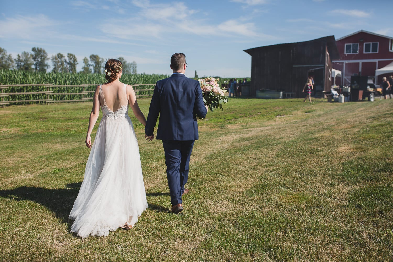 couple walking in field at fraser valley barn wedding at hopcott farms
